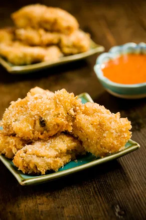 Paula Deen Southern fried oysters with a crisp golden panko coating on a green plate beside a bowl of orange dipping sauce
