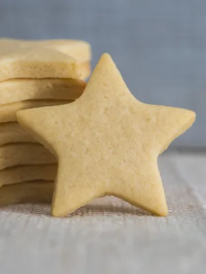 Paula Deen sugar cookie recipe star-shaped sugar cookie leaning against a stack of cut-out cookies