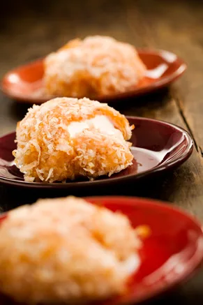 Paula Deen sweet potato balls rolled in toasted shredded coconut with a melted marshmallow center on red plates