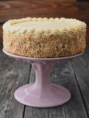 Paula Deen Tennessee banana-black walnut cake with caramel frosting and crushed walnuts on the sides, on a pink pedestal stand