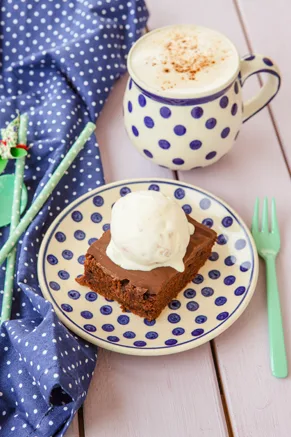 Paula Deen Texas sheet cake with chocolate fudge frosting served on a blue polka dot plate topped with vanilla ice cream