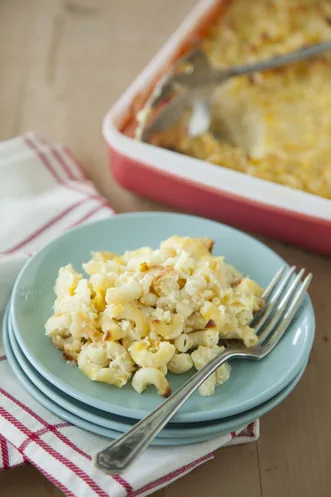 Paula Deen The Ultimate Lady's Cheesy Mac and Cheese served on a blue plate with a fork beside a baking dish of the baked casserole