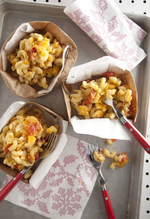 Paula Deen tomato basil mac and cheese mini casseroles served in paper-lined bowls with red-handled forks on a baking sheet