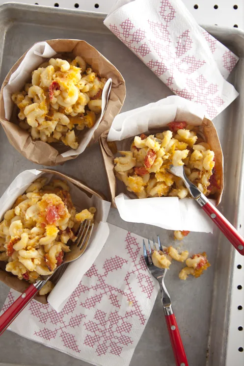 Paula Deen tomato basil mac and cheese mini casseroles served in paper-lined bowls with red-handled forks on a baking sheet