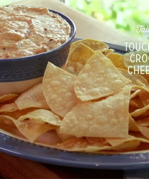 Paula Deen touchdown crockpot cheese dip in a blue bowl with homemade fried tortilla chips on an oval platter