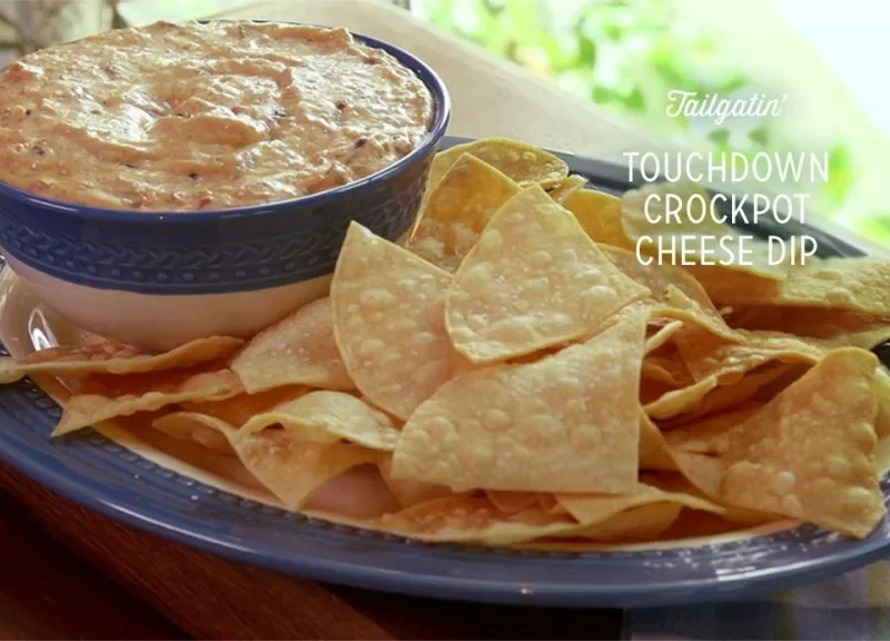 Paula Deen touchdown crockpot cheese dip in a blue bowl with homemade fried tortilla chips on an oval platter