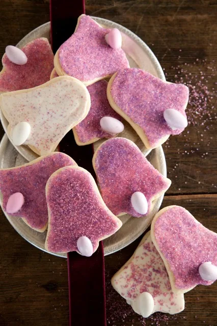 Paula Deen vanilla sugar cookie bell shapes with pink and purple sprinkles and pastel candy eggs on a plate
