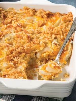 Paula Deen Vidalia onion casserole in a white baking dish with a golden cheesy cracker topping and a serving spoon