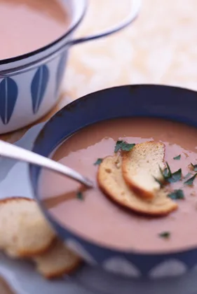 Paula Deen white bean soup in a blue bowl topped with chopped parsley and toasted bread slices