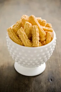 Paula Deen zesty cheese straws, golden ridged cheddar strips piled in a white hobnail glass bowl